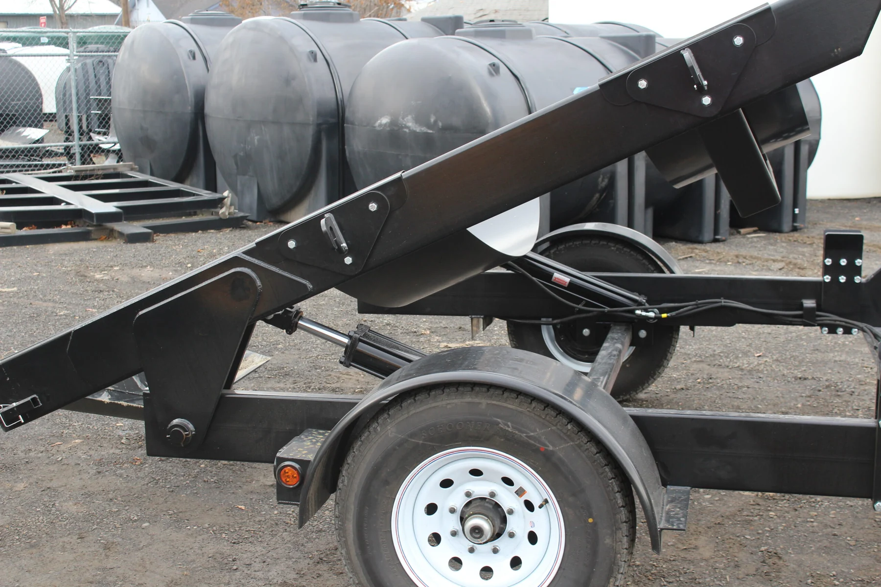 Close view of the tilt trailer’s hydraulic cylinders, tank supports, and steel frame Close view of the tilt trailer’s hydraulic cylinders, tank supports, and steel frame